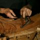 Artisan ébéniste sculptant méticuleusement des détails ornementaux sur un morceau de bois, illustrant l'évolution du mobilier et l'artisanat traditionnel.