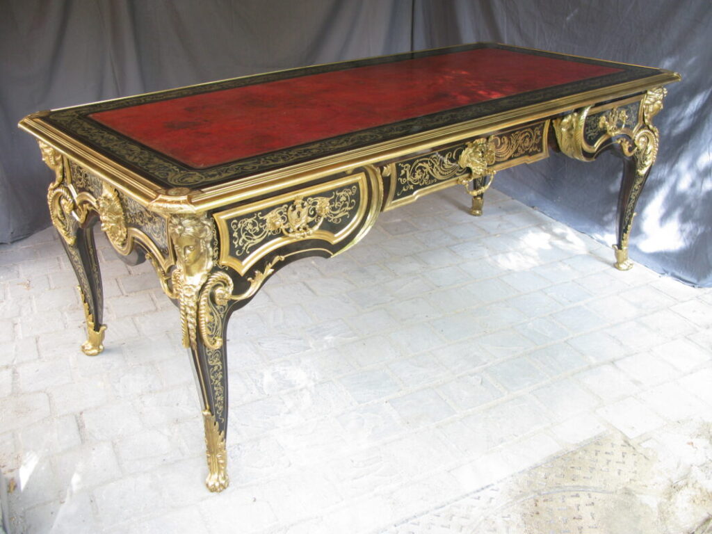 Grande table de style Boulle avec plateau en cuir rouge et marqueterie Boulle techniques ancestrales sur fond noir et dorures somptueuses.